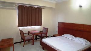 a bedroom with a bed and a table and chairs at Hotel Dot Com Entebbe in Entebbe