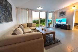uma sala de estar com um sofá, uma mesa e uma televisão em Danubio Residence em Aljmaš