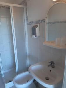 een badkamer met een wastafel, een toilet en een spiegel bij Hotel Grotte del Paradiso in Portoferraio