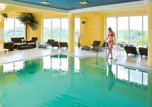 a woman is standing next to a swimming pool at Ringhotel Roggenland in Waldeck