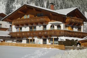 een groot houten huis in de sneeuw met een hek bij Haus Stern in Neustift im Stubaital