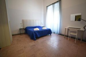 ein Schlafzimmer mit einem Bett mit einer blauen Decke und einem Schreibtisch in der Unterkunft TIFEO Bed & Breakfast in Catania