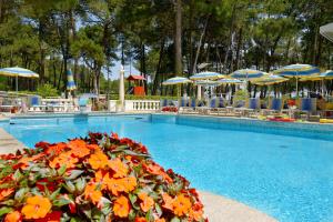 a swimming pool with umbrellas and tables and chairs at Residence Due Perle in Lignano Sabbiadoro