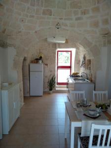 a kitchen with a table and a stove and a window at Trulli del boschetto in Putignano