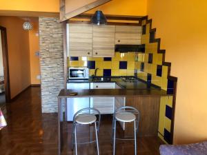 a kitchen with a counter and two stools at Camino Portugués Apartamentos in A Guarda
