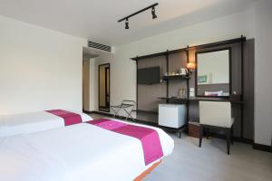 a hotel room with two beds and a desk at The Mantrini Chiang Rai-SHA Extra Plus in Chiang Rai