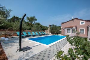 a swimming pool with lounge chairs next to a house at Villa Sunshine in Pula