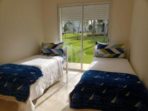 two beds in a room with a window at CASA BAY BEACH RETREAT in Sidi Rahal +27 photos