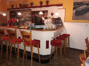 un bar en un restaurante con taburetes rojos en Rathausschenke Münstermaifeld, en Münstermaifeld