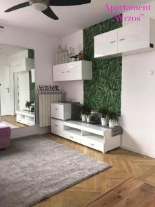 Elle comprend un salon doté d'un mobilier blanc et d'un mur vert. dans l'établissement DELUXE PAŃSKA APARTMENTS, à Varsovie