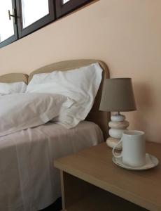 un letto con cuscini bianchi e un tavolo con una lampada di B&B "al Pesce Vela" ad Albese Con Cassano