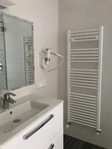 ein weißes Badezimmer mit einem Waschbecken und einem Spiegel in der Unterkunft B&B "al Pesce Vela" in Albese Con Cassano