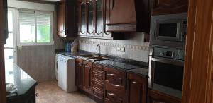 a kitchen with wooden cabinets and a sink and a microwave at Adosado GANDIA BEACH in Gandía