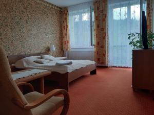 a bedroom with a bed and a chair and windows at Willa Jasna in Krynica Zdrój