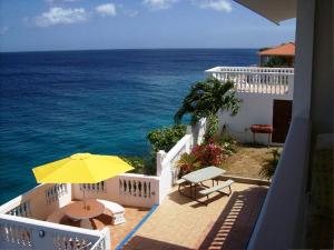 un balcón con una sombrilla amarilla y el océano en My Dream Apartments, en Lagun