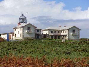 dom na szczycie wzgórza z latarnią morską w obiekcie Casa en Puerto de Bares w mieście Bares