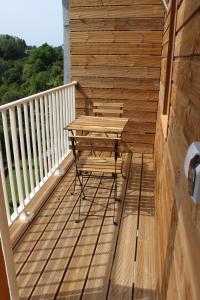 una terraza de madera con una mesa y una silla. en Bel appartement avec vue sur vézère, en Uzerche