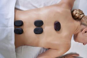 a woman laying in bed with black pills on her back at Antigoni Seaside Resort in Ormos Panagias