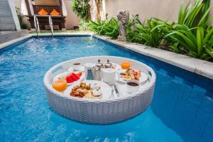 a breakfast table in the middle of a swimming pool at Aldeoz Grand Kancana Villas Resort Bali in Kerobokan
