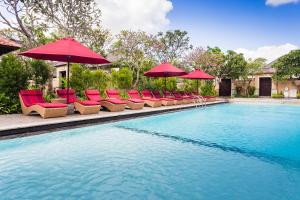a swimming pool with red umbrellas and chairs and a pool at Aldeoz Grand Kancana Villas Resort Bali in Kerobokan
