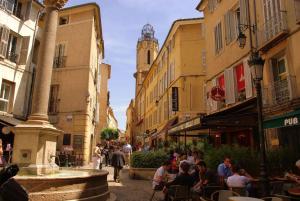 a group of people sitting in a street with a fountain at Studio ensoleillé, typique centre historique, wifi in Aix-en-Provence