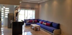 CASA BAY BEACH RETREAT في سيدي رحال: غرفة معيشة مع أريكة زرقاء مع وسائد ملونة