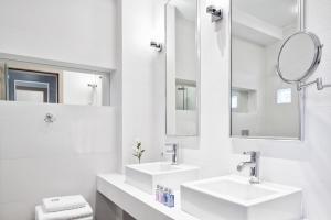 a white bathroom with two sinks and mirrors at Antigoni Seaside Resort in Ormos Panagias
