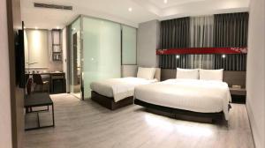 a hotel room with two beds and a desk at City Place Hotel in Tainan