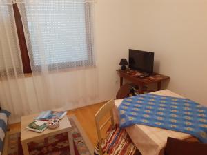 a room with a bed and a table and a television at Apartman Došen in Ličko Petrovo Selo