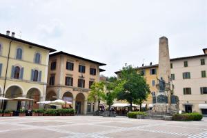 una piazza cittadina con edifici e monumento di Piazza Arnolfo 1932 a Colle Val D'Elsa