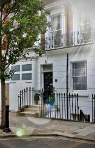 uma casa branca com uma cerca à frente. em Victoria Lodgings London em Londres