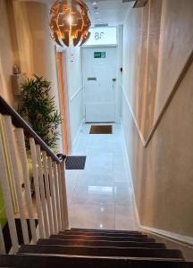 a hallway with a staircase with a door and a chandelier at Victoria Lodgings London in London