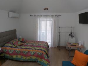 um quarto com uma cama, uma mesa e uma janela em Tipico Romântico II em Setúbal