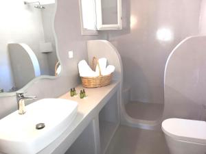een badkamer met een wastafel, een toilet en een spiegel bij Notos Villa in Skhoinoussa
