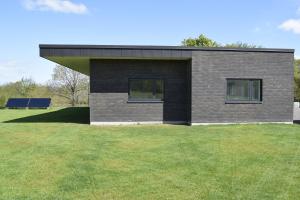 a house on a grassy field with a building at Fredensholm Annex in Skanderborg