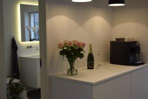 a vase of flowers on a counter with a bottle of wine at Fredensholm Annex in Skanderborg