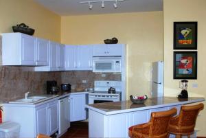 uma cozinha com armários brancos e electrodomésticos brancos em Ocean Terrace Condominiums em The Valley