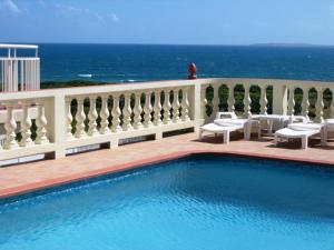 ein Schwimmbad mit dem Ozean im Hintergrund in der Unterkunft Ocean Terrace Condominiums in The Valley