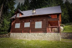 a log cabin with a stone wall in front of it at Triangle Woodhouse in Plav