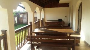 a porch with wooden tables and benches on a balcony at Agropensiunea Izana in Drăguţeşti