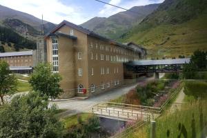 un gran edificio con un puente junto a una montaña en Les Forques de'n Pep, en Toses