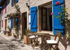 une table et des chaises devant un bâtiment avec volets bleus dans l'établissement Gîte Rue des Fleurs Puycelsi, à Puycelci