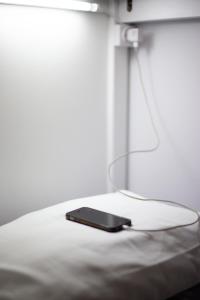 a cell phone laying on top of a bed at Hostel das Flores in Senhora da Hora