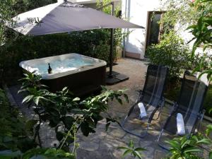 a hot tub with an umbrella and two chairs at Apartments Mrva in Ugljan