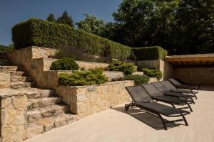 a row of benches sitting next to a stone wall at Perla Balaton in Csopak