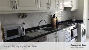 una cucina con mobili bianchi, un lavello e un microonde di Edificio Solmar Apartment ad Armação de Pêra