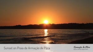un tramonto sulla spiaggia con il sole che tramonta sullo sfondo di Edificio Solmar Apartment ad Armação de Pêra Altre 3 foto