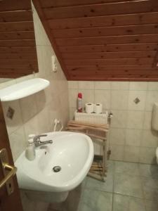 ギェネシュディアーシュにあるKovács Apartmanの木製の天井のバスルーム(白い洗面台付)