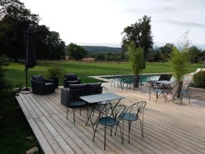 a wooden deck with chairs and tables and an umbrella at Cabane Aligoté in Saint-Albain