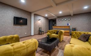 a living room with yellow couches and a flat screen tv at Travel Inn Kazbegi in Stepantsminda